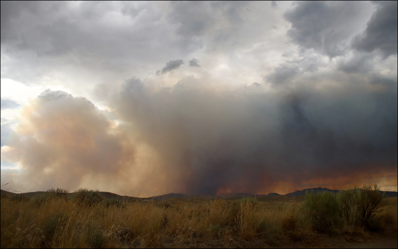 Image of a California hills fire with smoke clouds above.