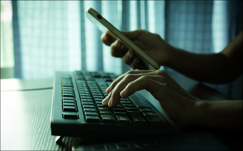 Person using keyboard and phone.