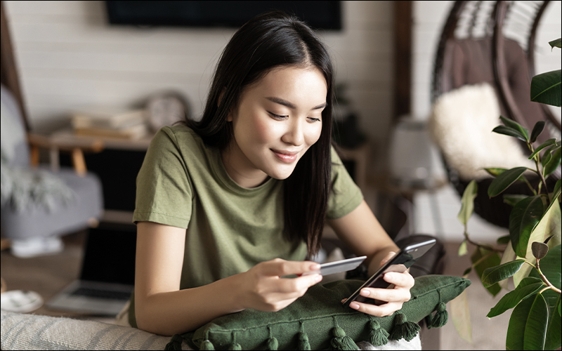 Woman holding credit card and phone, online shopping.