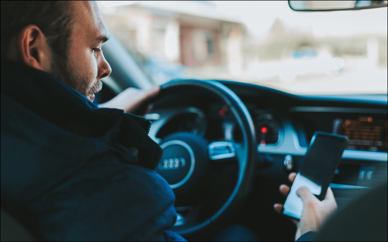 Man checking phone while driving.