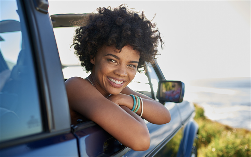 Woman smiling looking out her car window.