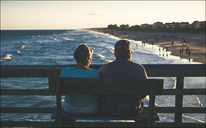 Retired couple sitting on a bench on a pier.