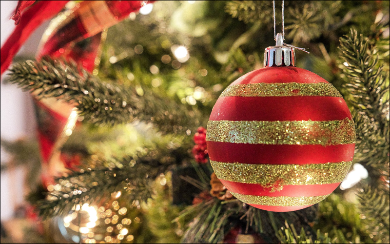 Gold and red striped ornament on a Christmas tree with lights.