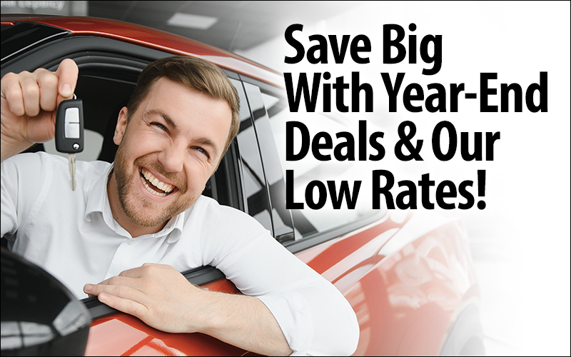 Save Big With Year-End Deals & Our Low Rates! Photo of man smiling in car holding keys.
