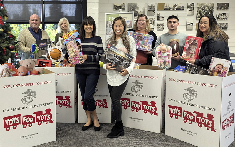 Photo of 1st Nor Cal staff holding toys in front of toy drive boxes.