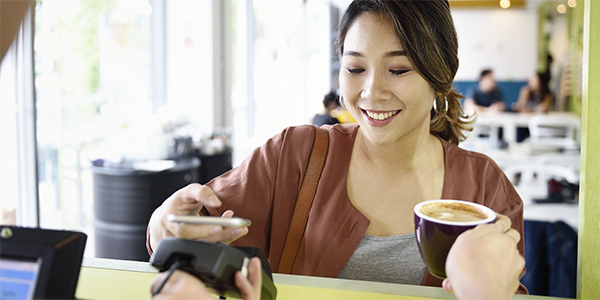 Woman using mobile banking to purchase coffee