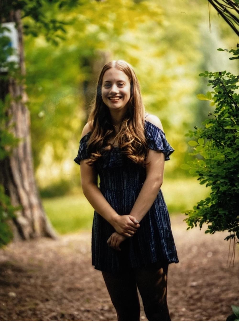 teenage girl in blue top standing on a dirt path