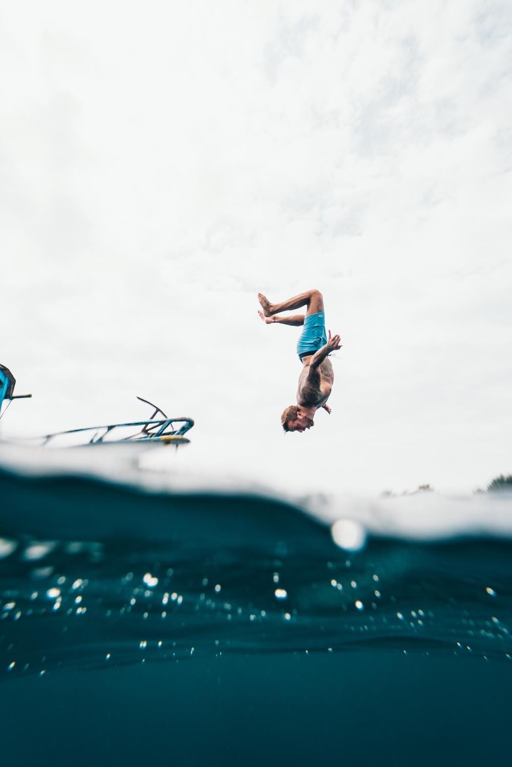 Man wearing blue shorts about to dive into water