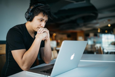 man with headphones looking at an open laptop