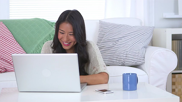 woman sitting in front of a couch while looking at a laptop