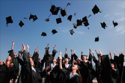 group of youth in graduation gowns throwing caps in the air