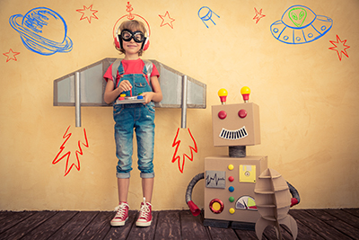 child standing next to a cardboard robot