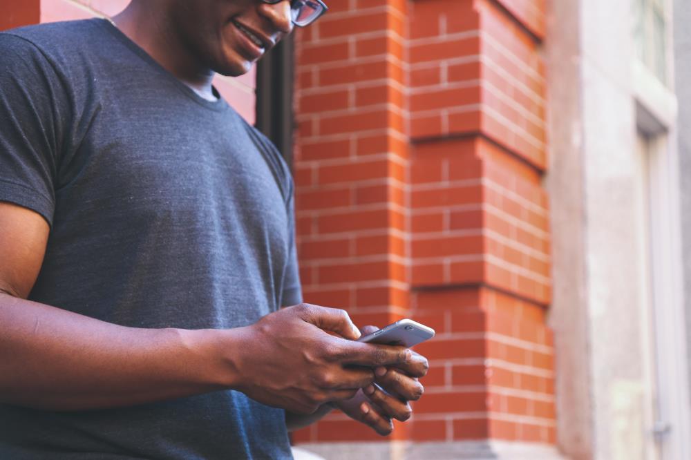 man in a grey shirt looking at a cell phone