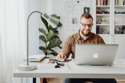 man sitting at a desk in front of a laptop