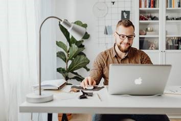 man sitting at a desk looking at a laptop